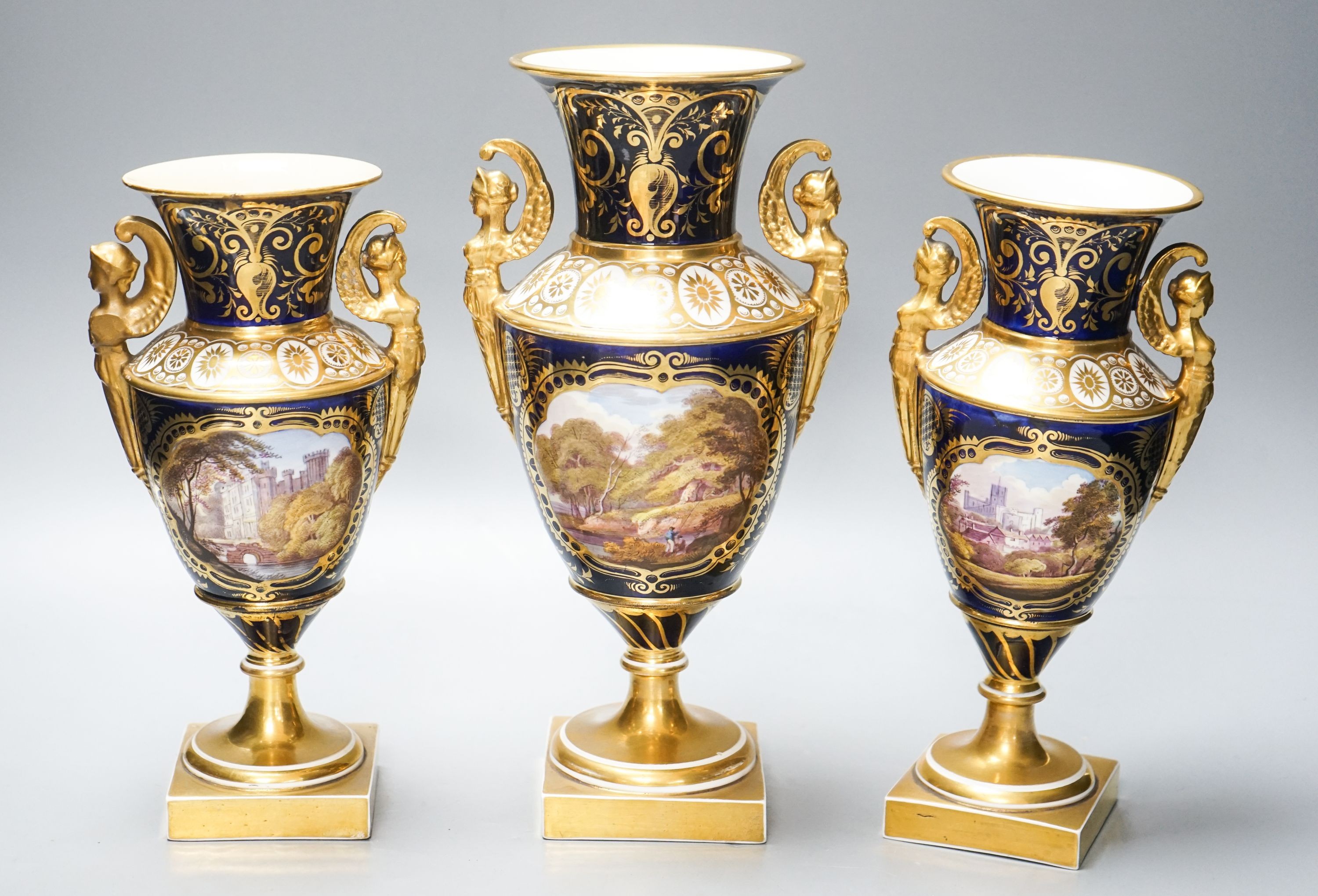 A garniture of three early 19th century English porcelain vases, c.1815-20, each painted with topographical views, tallest 26cm